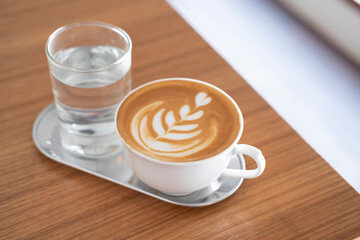 Hot latte serve with still water serve on wooden table