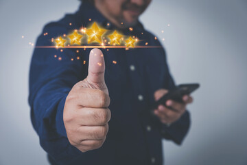 Businessman show hand thumb rises up with virtual five yellow stars. Evaluation the customer satisfaction and service. Products and service evaluation concept.