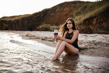Attractive woman with long hair enjoying evening at resort restaurant terrace. Silhouette of her beautiful body ( no face ) and glass of wine in contrast with the amazing view of blue sea and islands