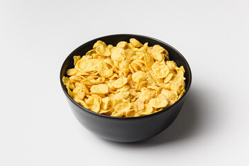 Corn flakes in dark bowl on white background.