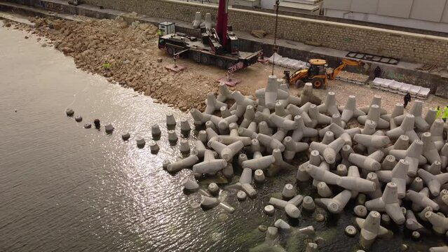Aerial view of breakwater construction. Bulldozer and crane on a pile of boulders in the sea	