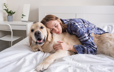 A young woman is happily spending time with her purebred dog. Girl scratching her golden retriever...