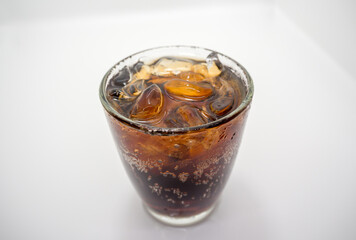 Close-up, soft drink and ice in a curved clear glass, white background