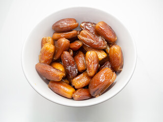 High Angle, stack of dates palm(Phoenix dactylifera) in white bowl, white background and copy space.