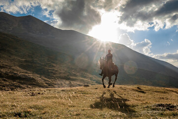 Rider Caucasian girl on a horse gallops through a mountain valley