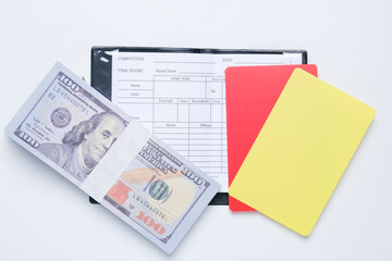 A picture of cash on match detail sheet and red with yellow card. Match fixing concept.