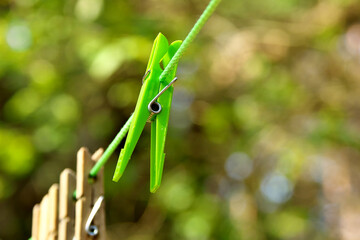 A green plastic clothespin on a green rope. Selective focus.