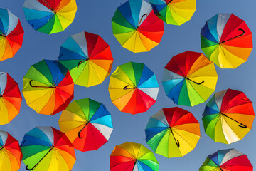 Fototapeta na wymiar Rainbow-colored umbrellas in the blue sky