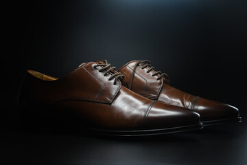 Photo of dark brown shoes on black background