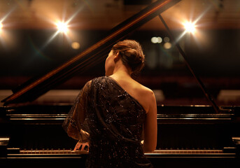Performing for the audience. Shot of a young woman playing the piano during a musical concert.