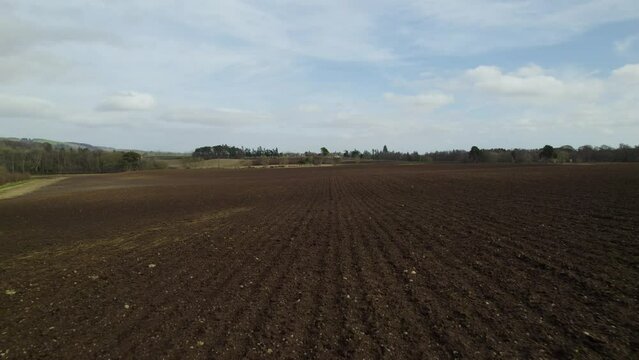 Drone flying low over freshly ploughed fields in Scotland