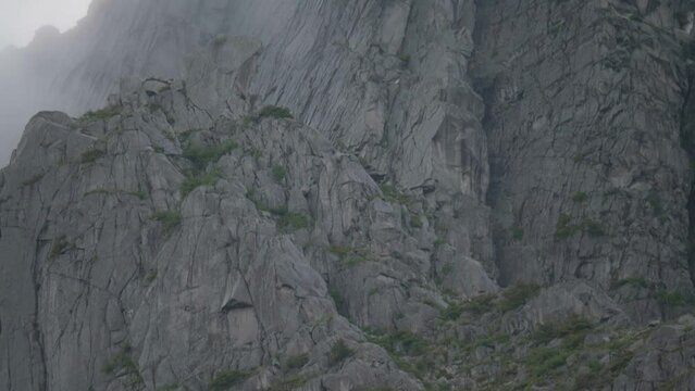 Close-up of a huge granite wall from the botom to the top on a cloudy day.