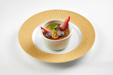 Dessert creme brulee in a plate on a white tablecloth. Close-up