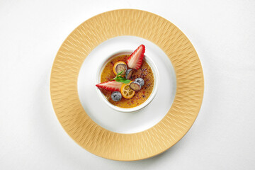 Fototapeta na wymiar Dessert creme brulee in a plate on a white tablecloth. Close-up