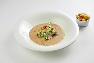Mushroom cream soup in a plate on a white tablecloth