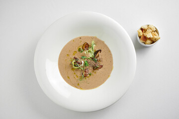 Mushroom cream soup in a plate on a white tablecloth