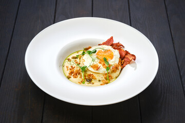 Fried egg with bacon slices and chips