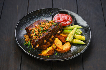 Grilled pork ribs with potato wedges and cucumber