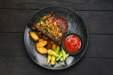 Overhead view of grilled pork ribs with potato wedges and cucumber