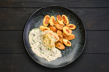 Overhead view of chicken fillet with gnocchi and mushroom sauce