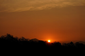 Sunset view with silhouettes of mountains, beautiful golden rays of sun in the background.