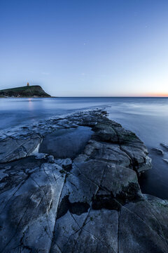 Vertical Shot Of A Blue Dusk Sky Over A Rocky Shore