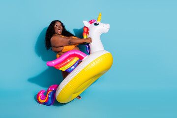 Portrait of attractive amazed cheery thick woman riding fairy horse fooling isolated over bright...