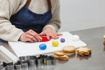 Crop baker cutting colorful gum paste in bakery