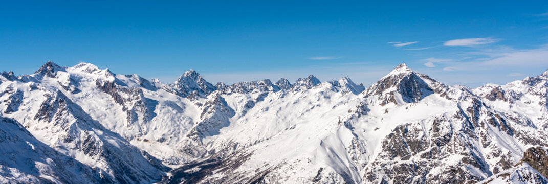 Panoramic view of winter snowy mountains in Caucasus region in Russia with blue sky