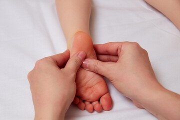 Doctor performing pediatric foot massage to prevent development of flat feet - 494412542