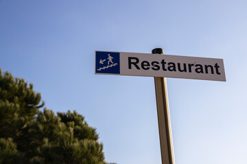 Pointer on a pillar with the inscription restaurant. On the embankment against the background of the sky pointer to the restaurant.