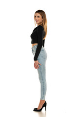 Charming young woman posing in studio in black short blouse , blue jeans