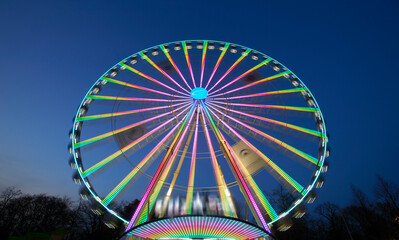 Fototapeta premium huge colorful ferriswheel rotating on a funfair in a blue summer night