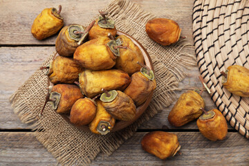 Bowl with tasty dried persimmon fruits on wooden table, flat lay