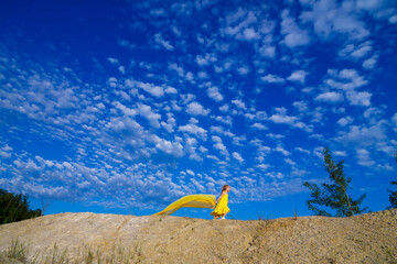 Fototapeta na wymiar Ukrainian patriot girl in a yellow dress against a blue sky. Summer photo. Blue sky. Sunny day. Free Ukrainian child. Child symbol of Ukraine