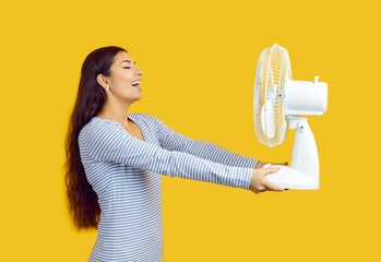 Device for cooling air. Satisfied woman suffering from heat enjoys cold air from electric fan on...