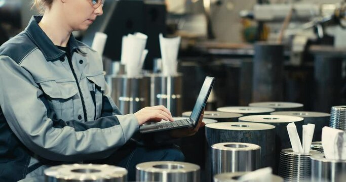 Oil refinery plant engineer in work uniform using laptop computer with spreadsheet software. Work with software at an oil-producing industrial enterprise intended for the production of parts.