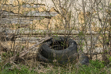 Fototapeta na wymiar Old used rubber car tire discarded on raw forest ecosystem,environmental pollution.