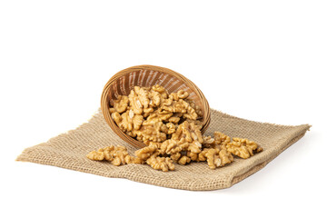 Overturned basket with peeled walnuts on burlap isolated on white background.