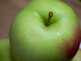 A large green apple, a close-up shot. A wet apple.