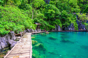 Kayangan Lake - Blue crystal water in paradise lagoon - walkway on wooden pier in tropical scenery...