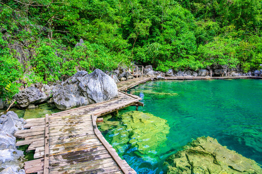 Kayangan Lake - Blue crystal water in paradise lagoon - walkway on wooden pier in tropical scenery - Coron island, Palawan, Philippines.
