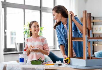 family, diy and home improvement concept - happy smiling mother and daughter with ruler measuring old wooden table for renovation at home