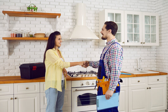 Smiling male plumber shake hand of happy female client or customer greeting come for visit. Repairman or mechanic handshake woman thanking for good quality plumbing service fix repair kitchen pipe.