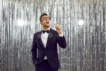 Popular male singer with microphone performing on stage. Handsome confident black man in trendy...