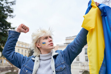 Caucasian man holding Ukrainian flag and looking at it with pride