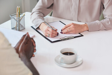 High angle shot of unrecognizable African American man sitting at table in front of his colleague...