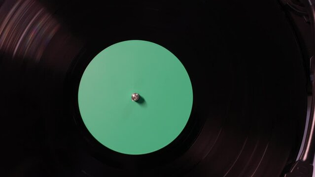 Vinyl retro record on DJ turntable record player. Black vinyl background with green screen in center.