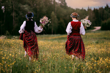 Latvian folk girls in traditional costume. Latvia summer. Symbolism of Latvia for Ligo holiday. Midsummer in Latvia. Traditional Latvian midsummer food. Celebration of Ligo in june decorating home wit - obrazy, fototapety, plakaty