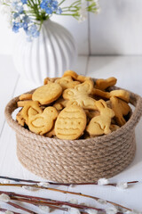 Easter cookies in a wicker basket with willow branches in the foreground